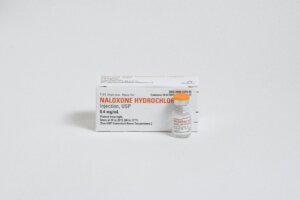 Photo of a vial of naloxone sitting in front of a box of naloxone.